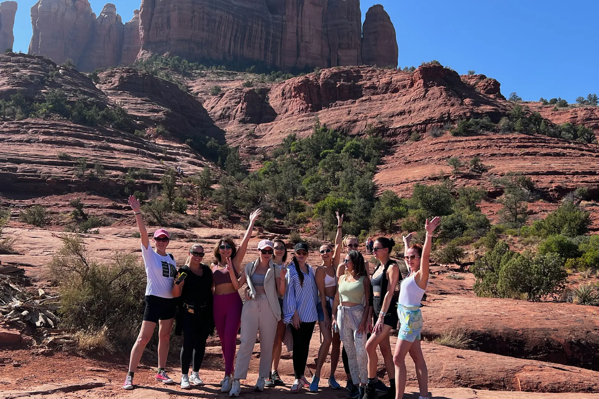 A group with arms raised in front of Cathedral Rock, Sedona