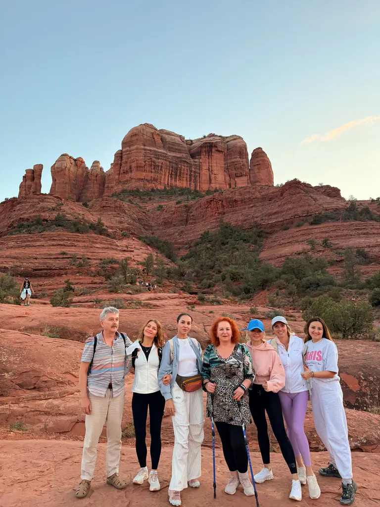 A group standing together on the red rock in front of Cathedral Rock, Sedona