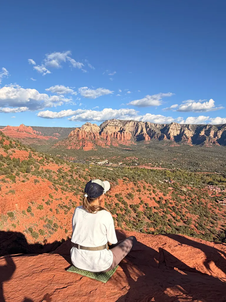 A woman sitting alone on the red rock, looking out over the Sedona valley